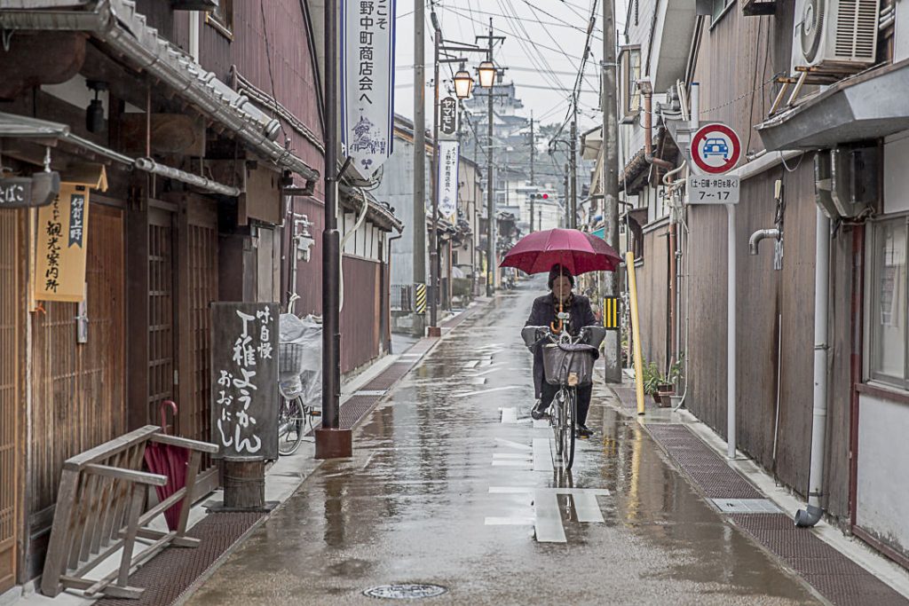 A Iga à vélo, avec un parapluie et des manches chauffantes