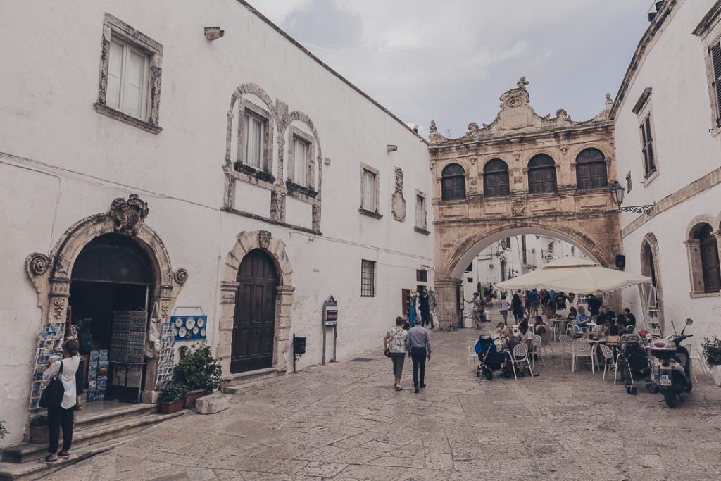 Personnes se baladant dans le rues d'Ostuni avec des terrasses de café