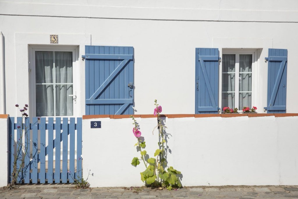 maison blanche aux volets bleus et rose trémière à Noirmoutier