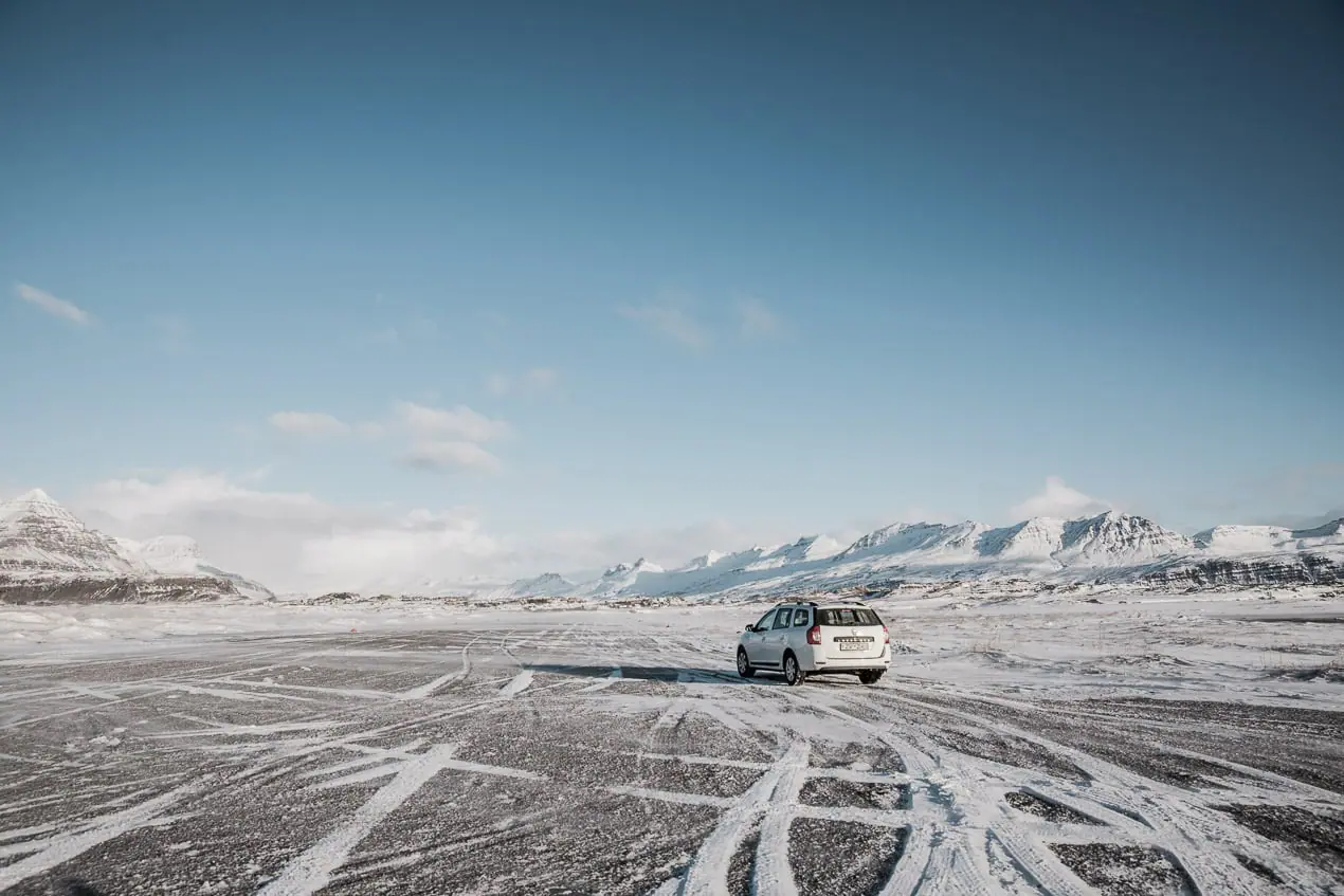 Dacia logan sur les routes d'islande enneigées en hiver sous un ciel bleu clair