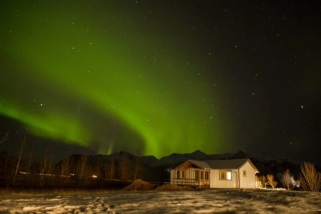 aurore boréale derrière une ferme en Islande