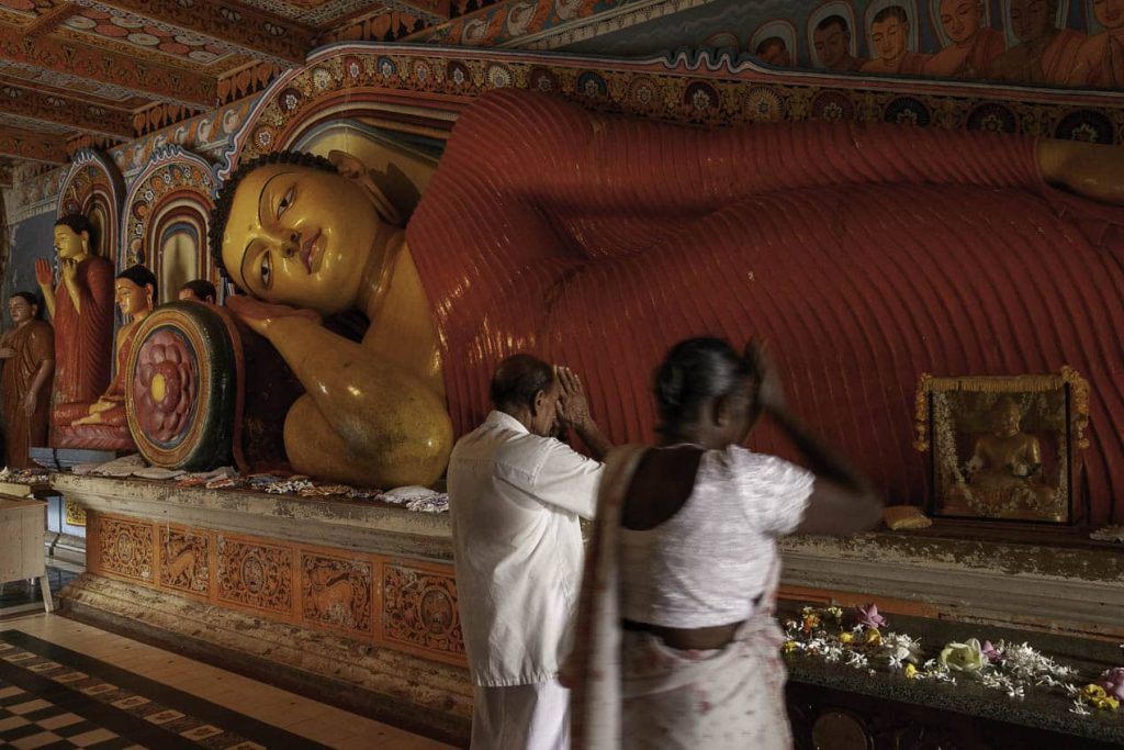 Prière devant un bouddha très coloré d'Anuradhapura