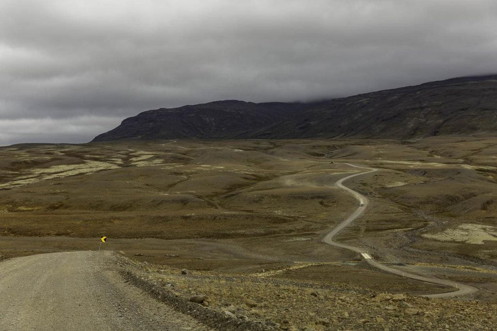 route sinuant dans un désert minéral au centre de l'Islande, au loin des montagnes