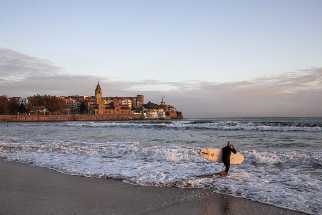 Personne allant surfer dans l'océan atlantique sur la plage de San Lorenzo à Gijon