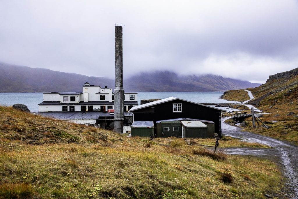 Grand batiment en béton de l'ancienne usine de hareng de Djupavik au nord ouest de l'Islande. Témoignage du passé économique de la région, ce site abandonné contraste avec la nature brute qui l’entoure.