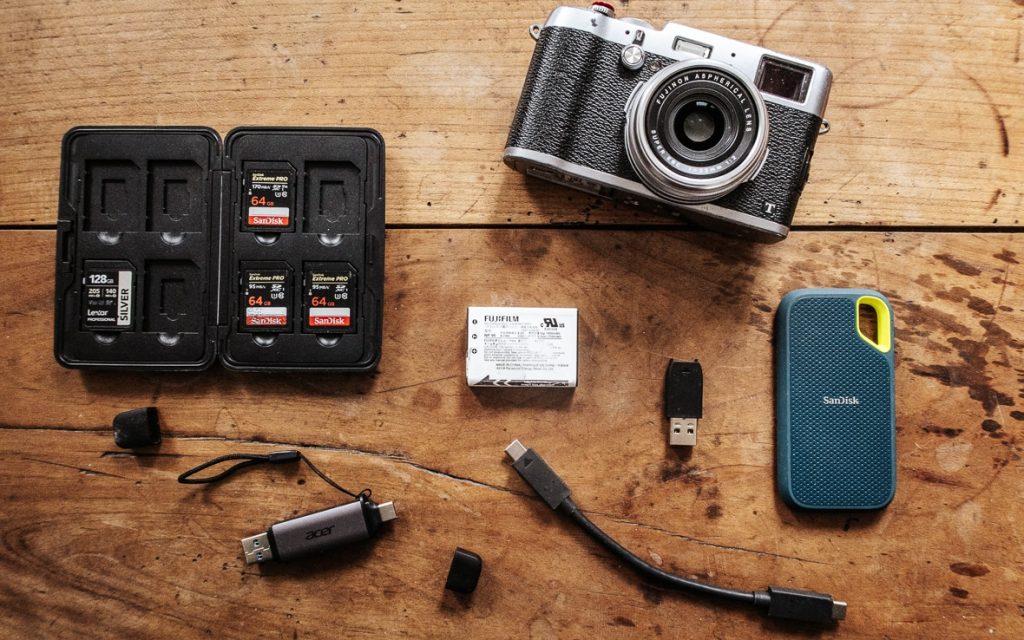 Divers accessoires photos à prendre en voyage posés sur une table