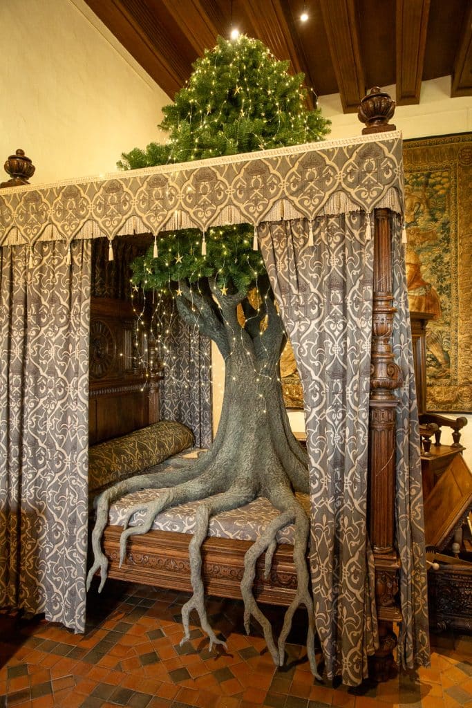 sapin de noël sur un lit royal avec racines descendant vers le sol