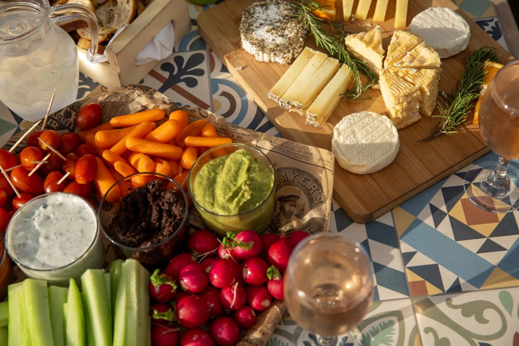 planche apéritive mélangeant fromage et légumes crus accompagnées d'un verre de rosé